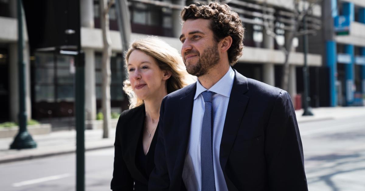 Elizabeth Holmes smiles as she walks with her husband Billy Evans.