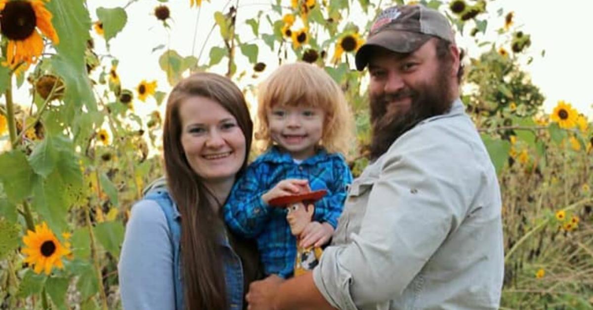 Thomas Jacob Sanford with his wife and son in a sunflower field.