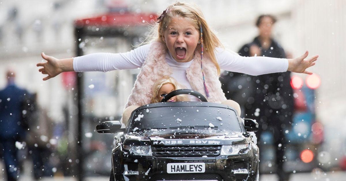 Girl in toy car with doll