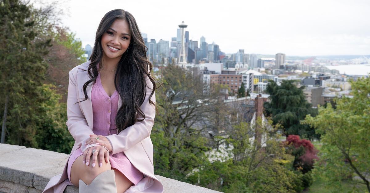 Jenn Tran on a stone wall near the Seattle skyline