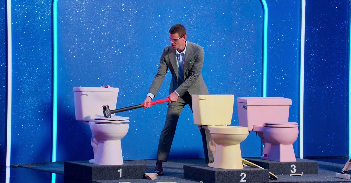 Mikey Day uses a sledgehammer on a toilet cake during a Season 2 episode of 'Is It Cake?'