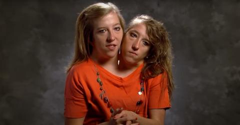 Abby and Brittany Hensel Spotted Holding Newborn Baby