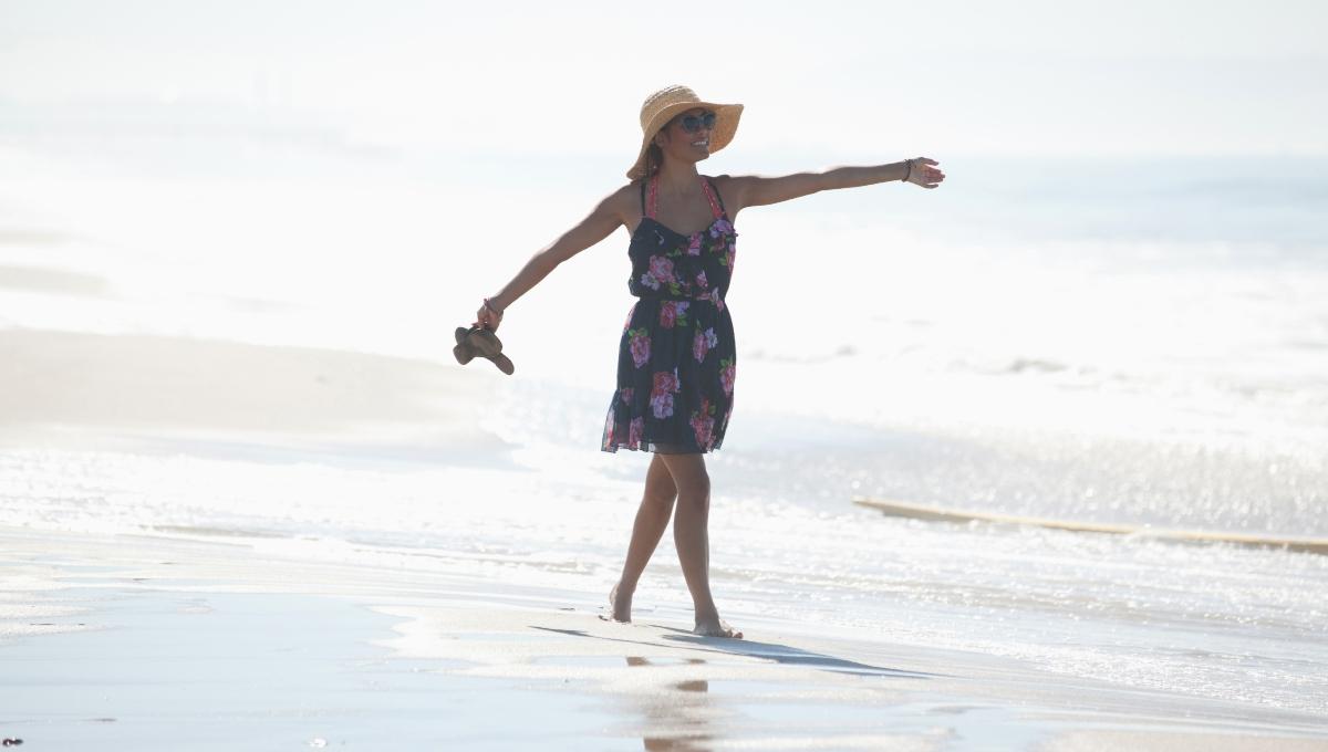 Woman carrying sandals on beach