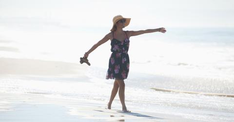 Woman carrying sandals on beach