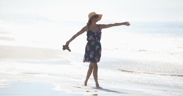 Woman carrying sandals on beach