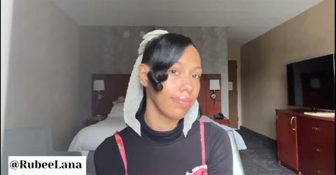 Rubee Lana sitting in front of her bed in a hotel room.