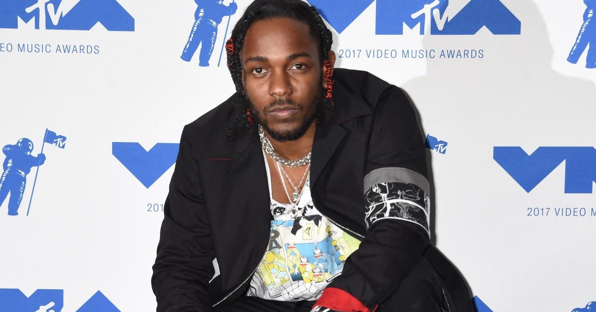 Kendrick Lamar leaning down for a press photo