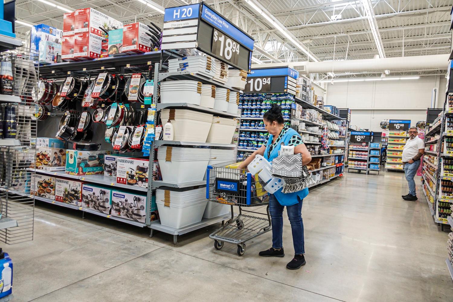 A Walmart employee replenishes items in a shopping cart.