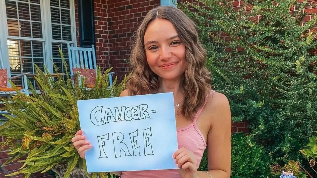 Alayna Hester holding a 'cancer free' sign