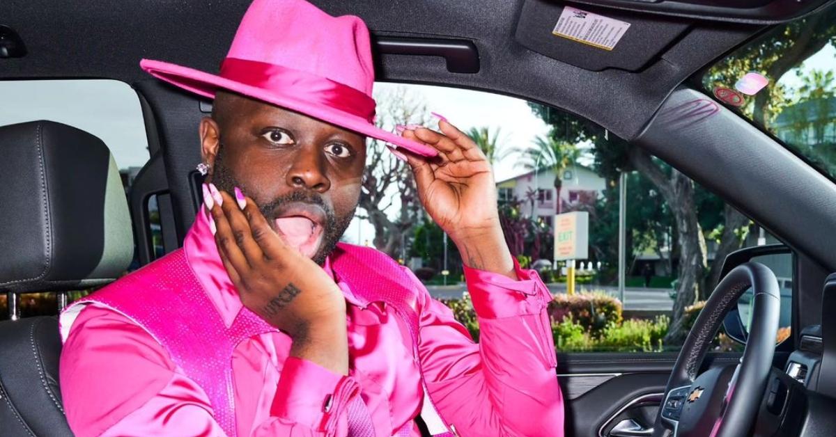 Bob the Drag Queen in a pink suit and hat in his car