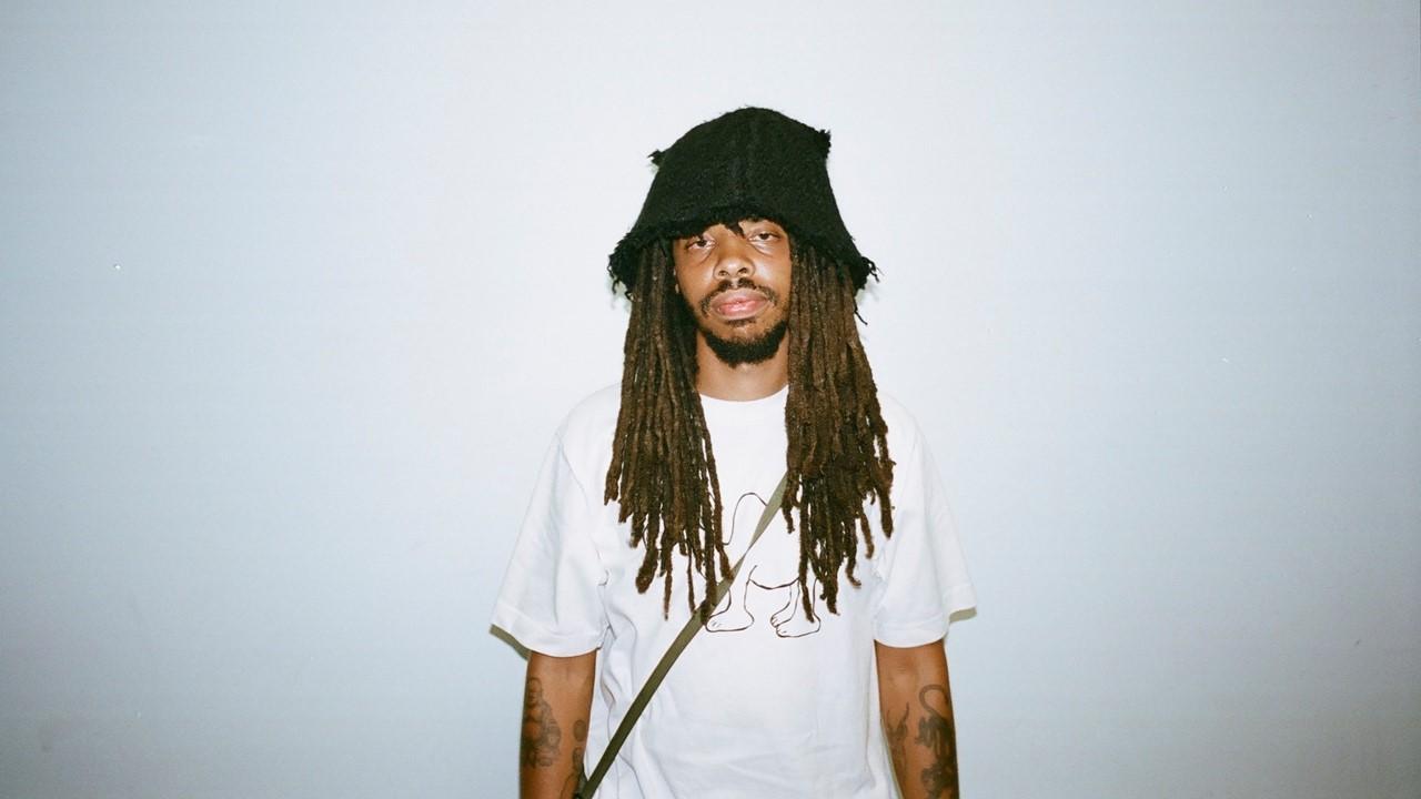 Earl Sweatshirt wearing a white t-shirt and black hat