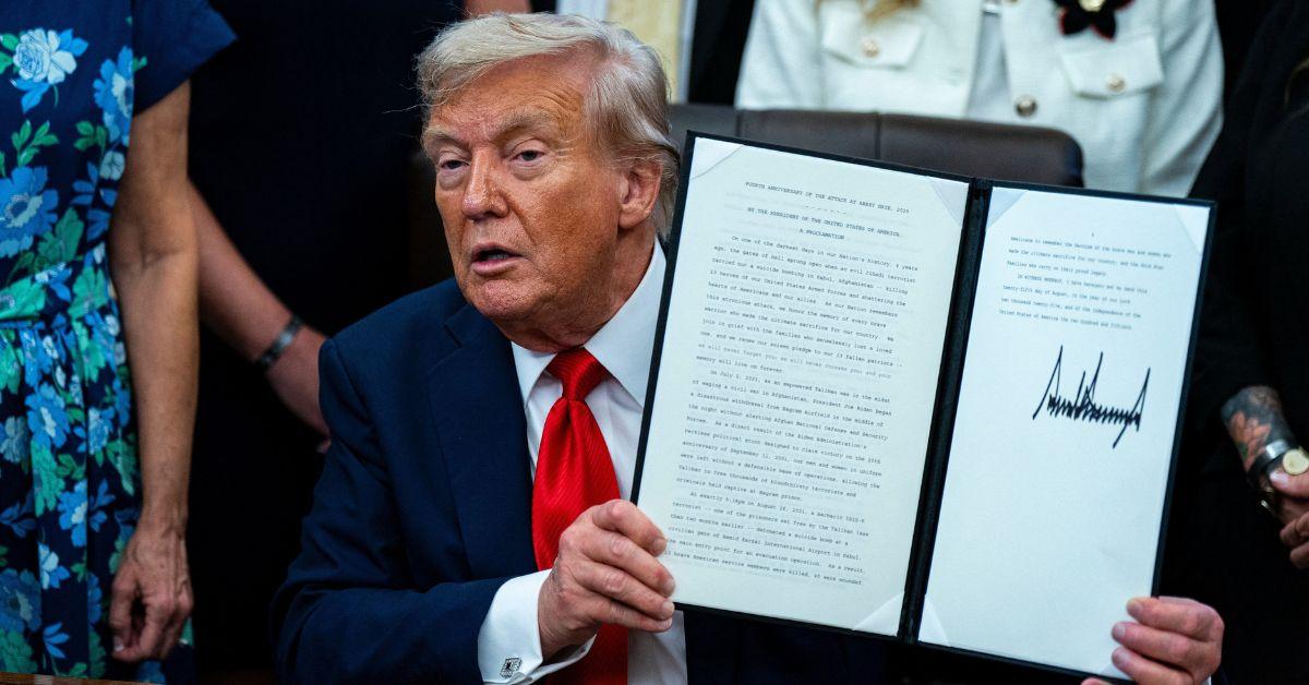 Donald Trump holding up a signed declaration in the Oval Office.