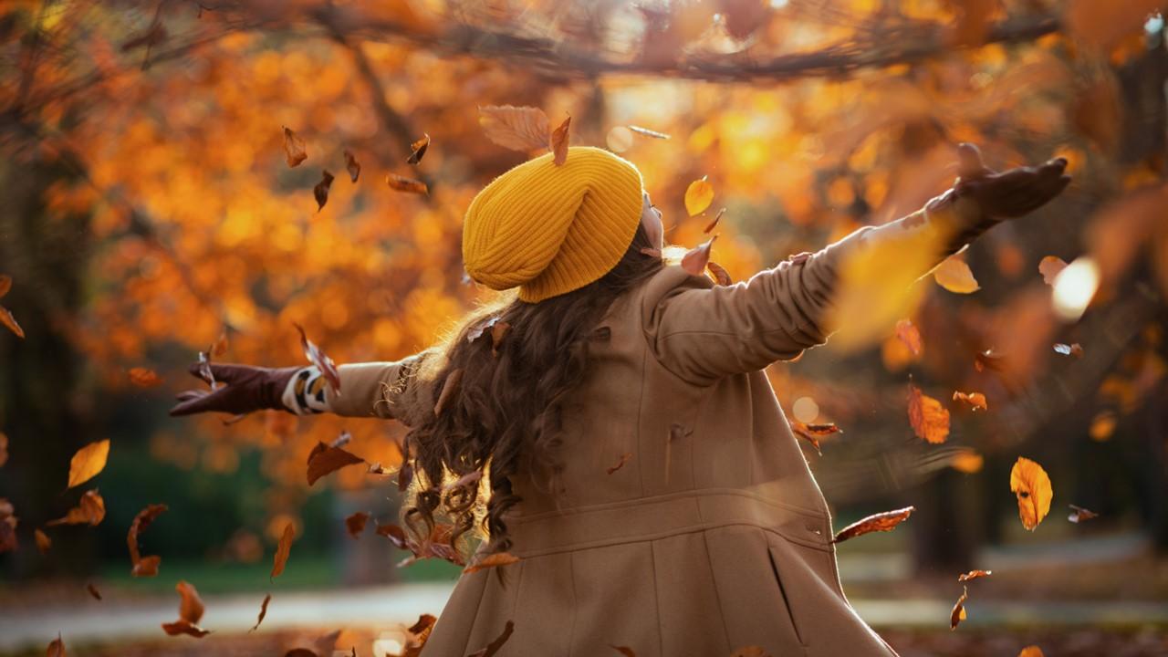 A woman dancing in the autumn as the leaves fall