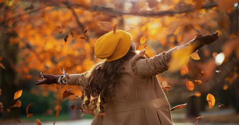 A woman dancing in the autumn as the leaves fall