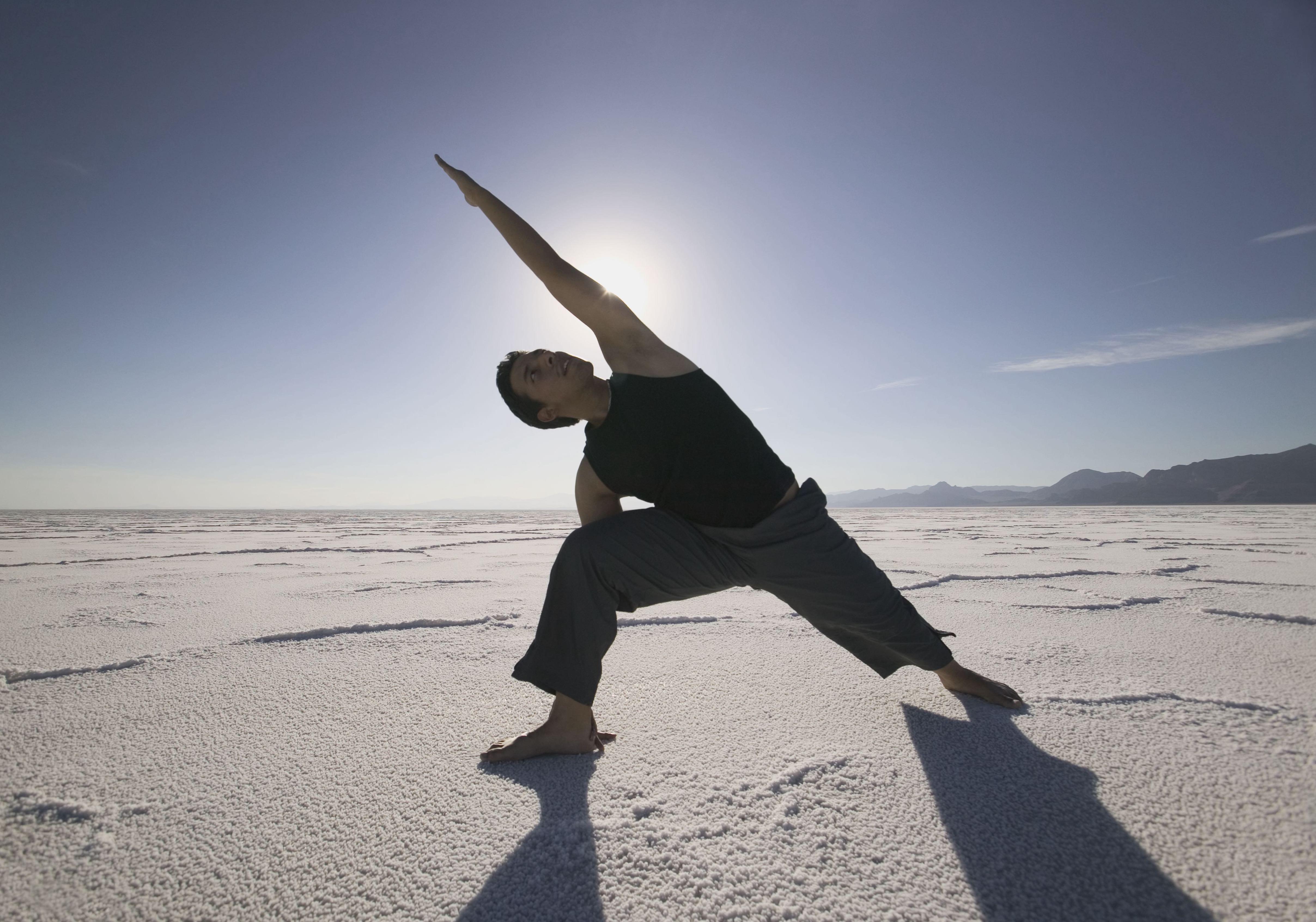 A man practices yoga in a wide open desert setting.