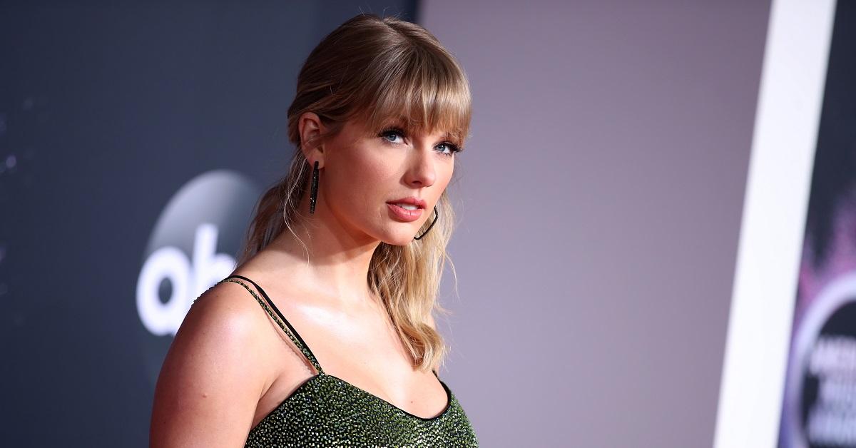 Musician Taylor Swift wearing a green dress on the red carpet of an awards ceremony.