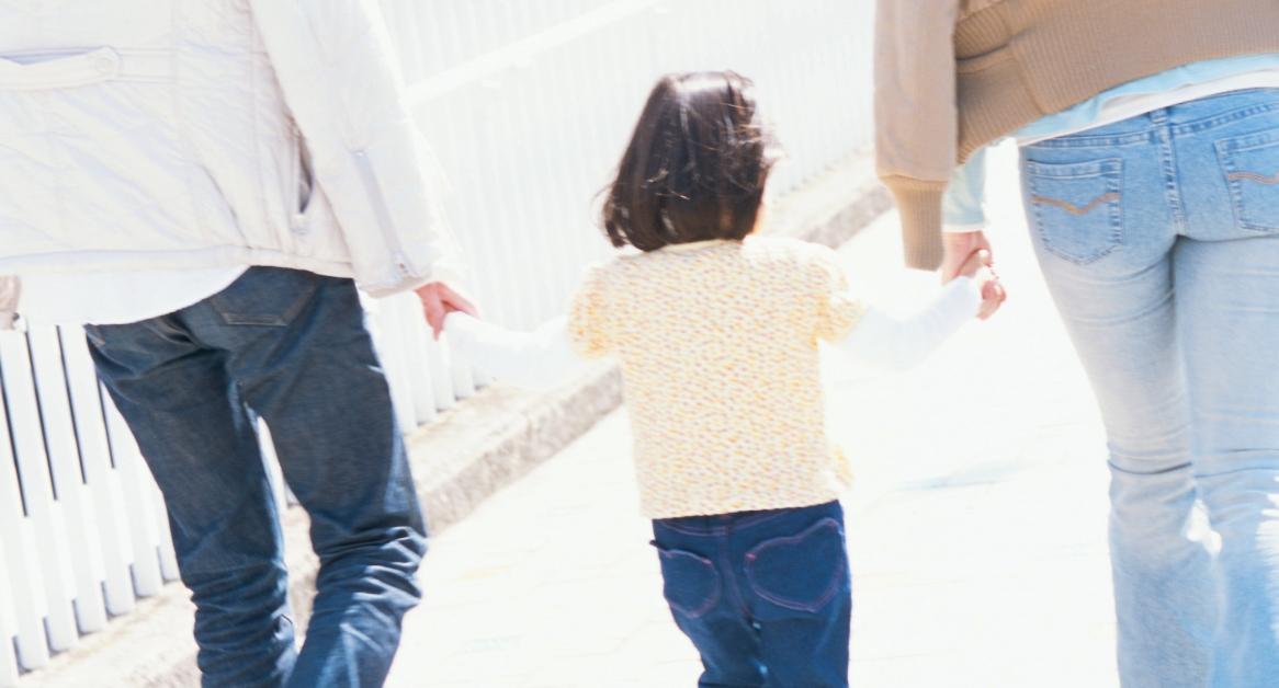 little child walking between parents while all holding hands