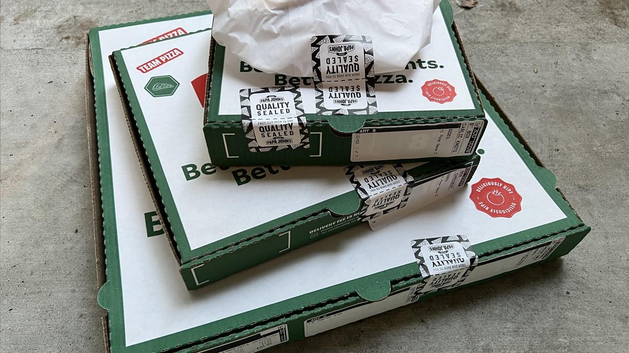 Egy Papa Johns rendelés a betonon ülve