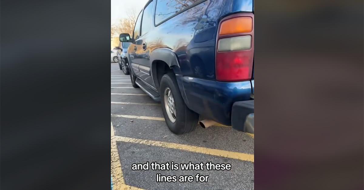 An SUV parked over the lines next to a handiapped spot