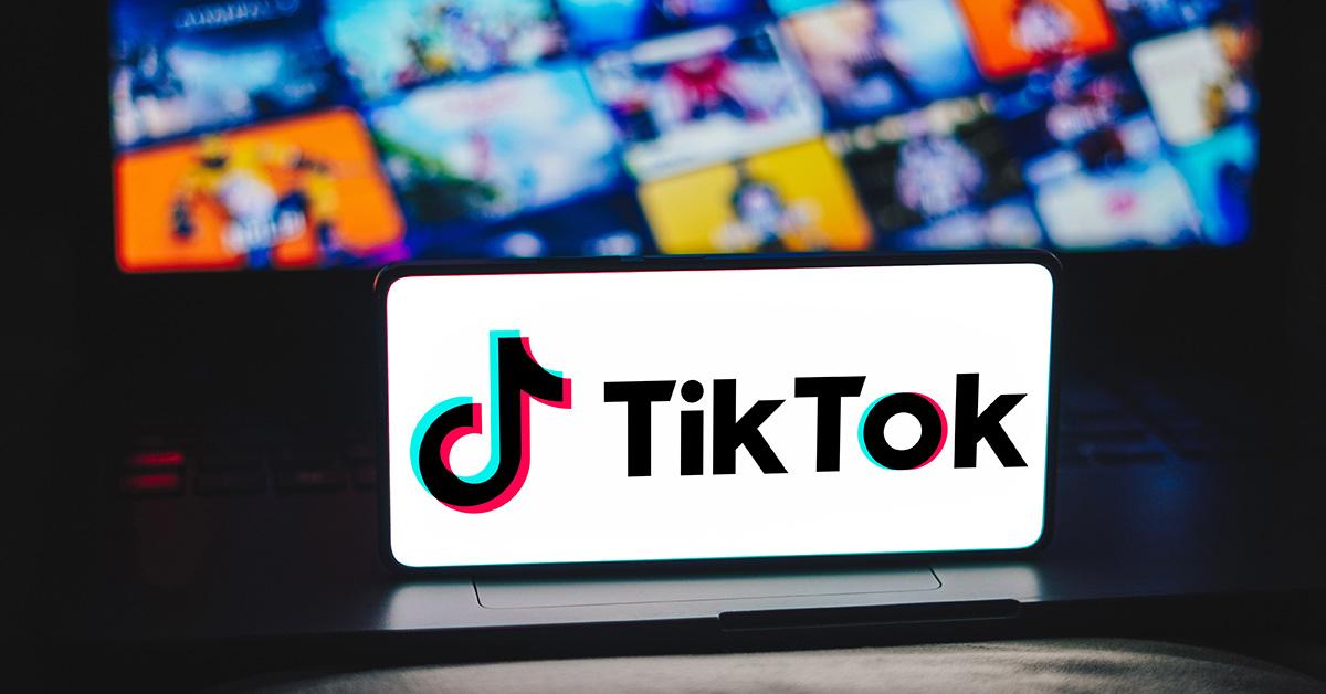 A TikTok logo on a phone screen with a laptop behind it. 