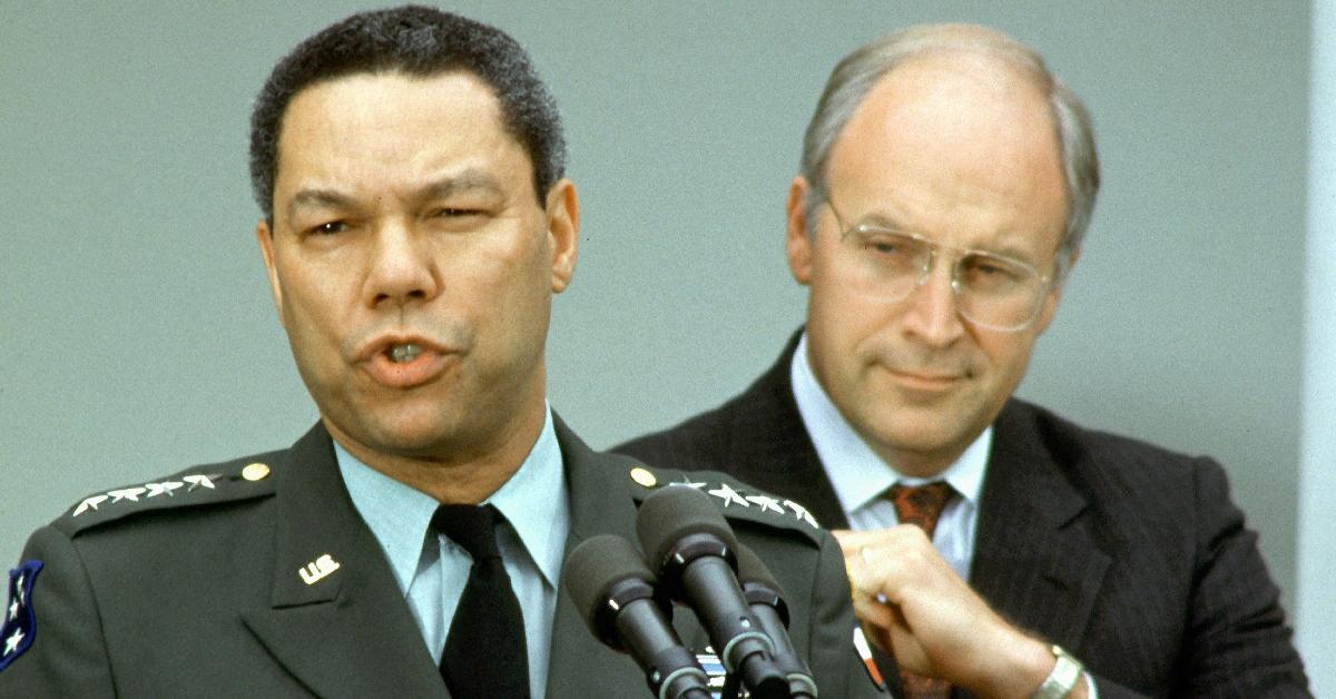 Dick Cheney (R) stands behind Colin Powell (L) in a press conference.