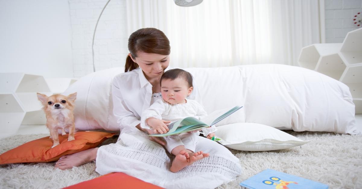 A mother reading to her baby with her dog.