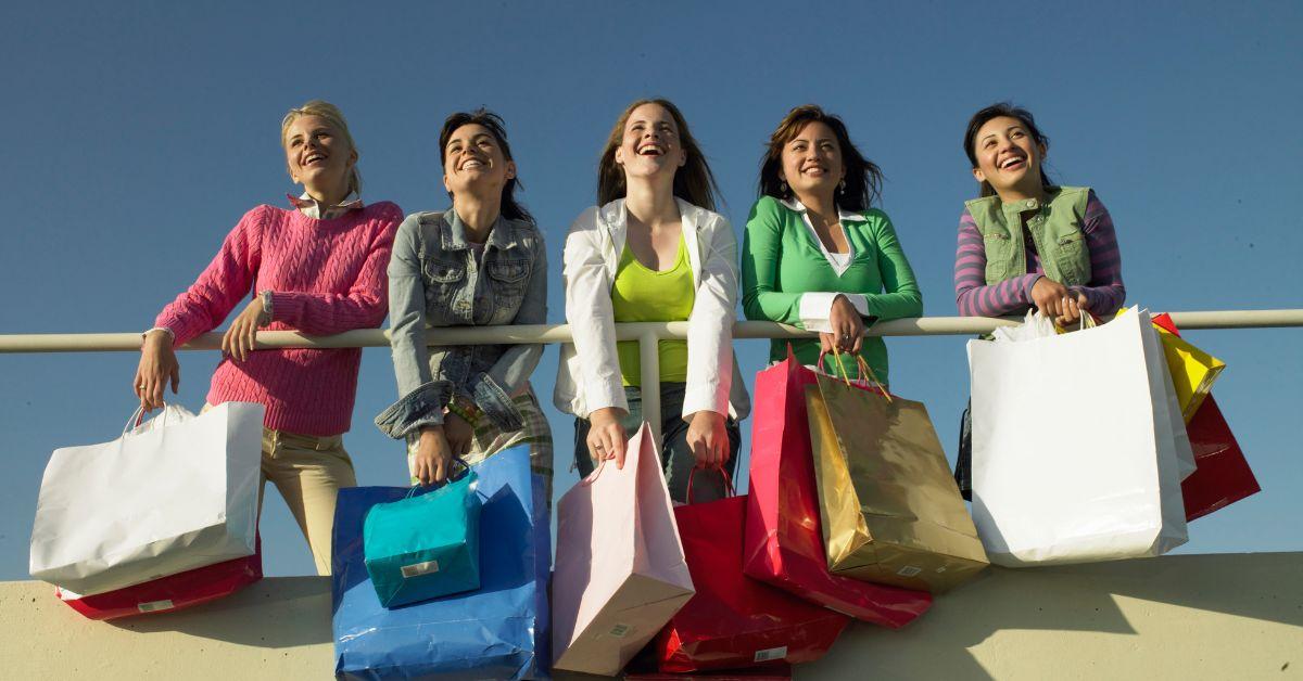 Teenage girls with shopping bags leaning on railing