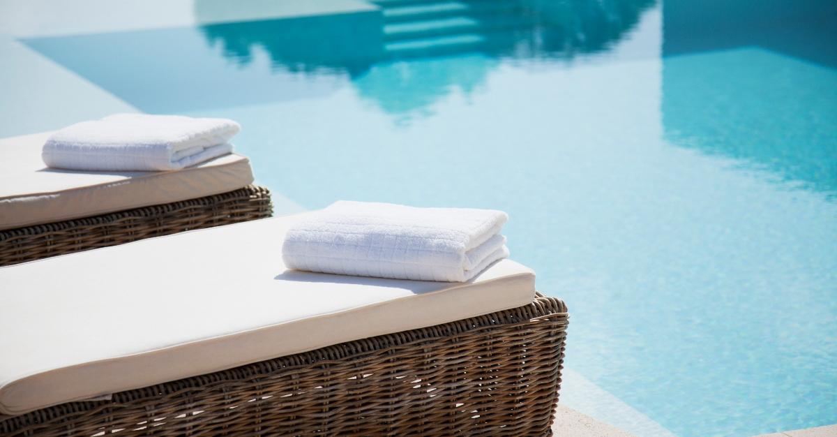 Folded towels on lounge chairs beside pool - stock photo