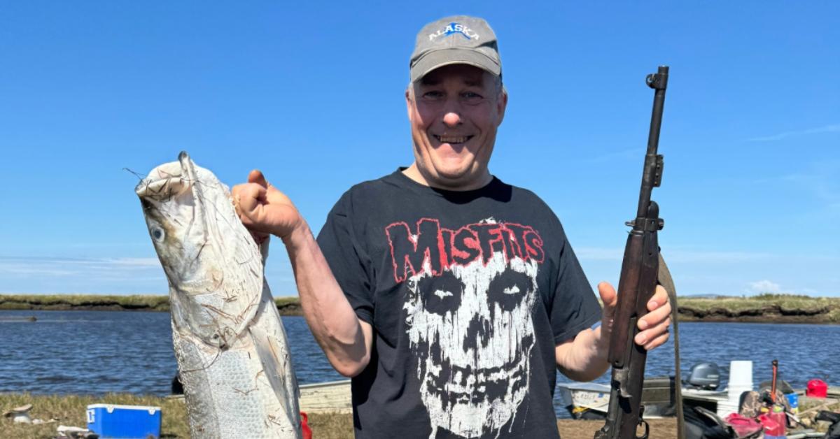 Chip Hailstone holding a fish and a hunting gun.