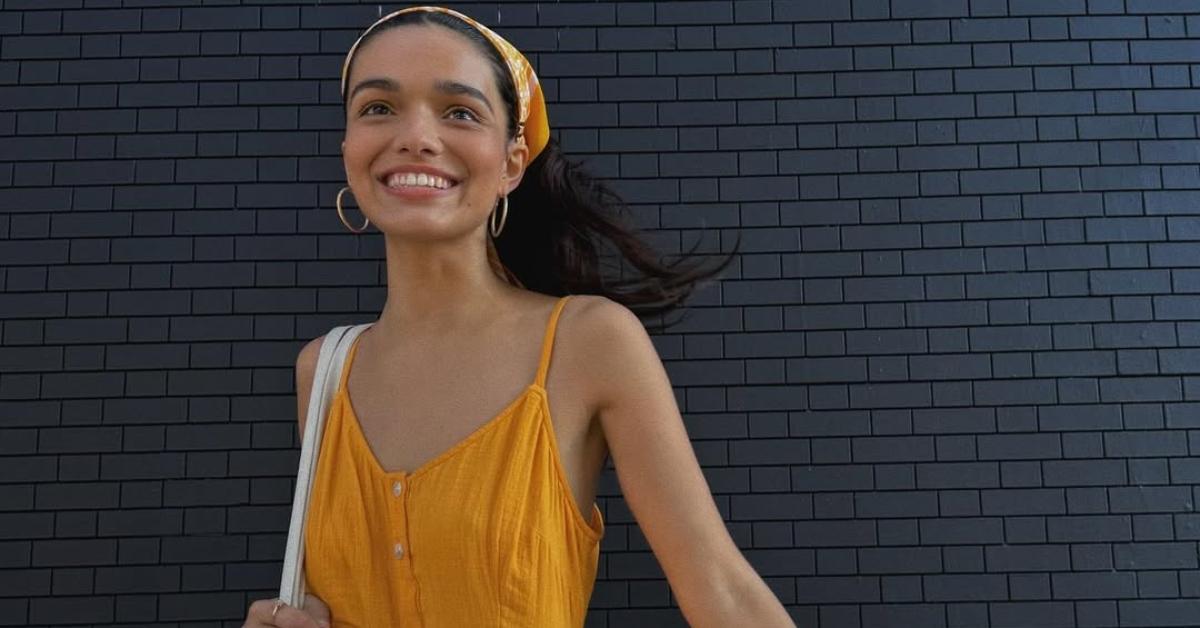 Rachel Zegler in a yellow dress outside.