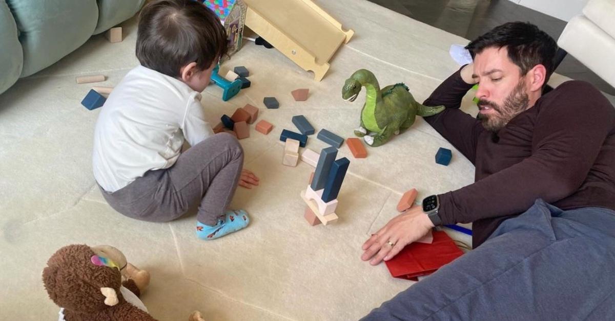 Drew Scott playing on the floor with his first born.