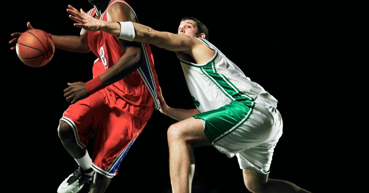 two men playing basketball against a black background