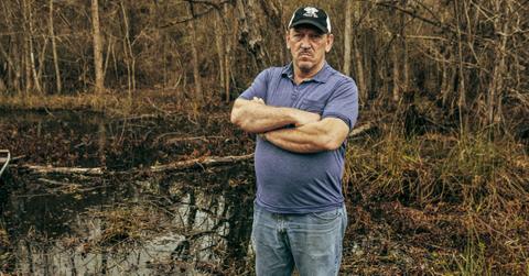 Troy Landry standing in a swamp with his arms crossed on 'Swamp People'