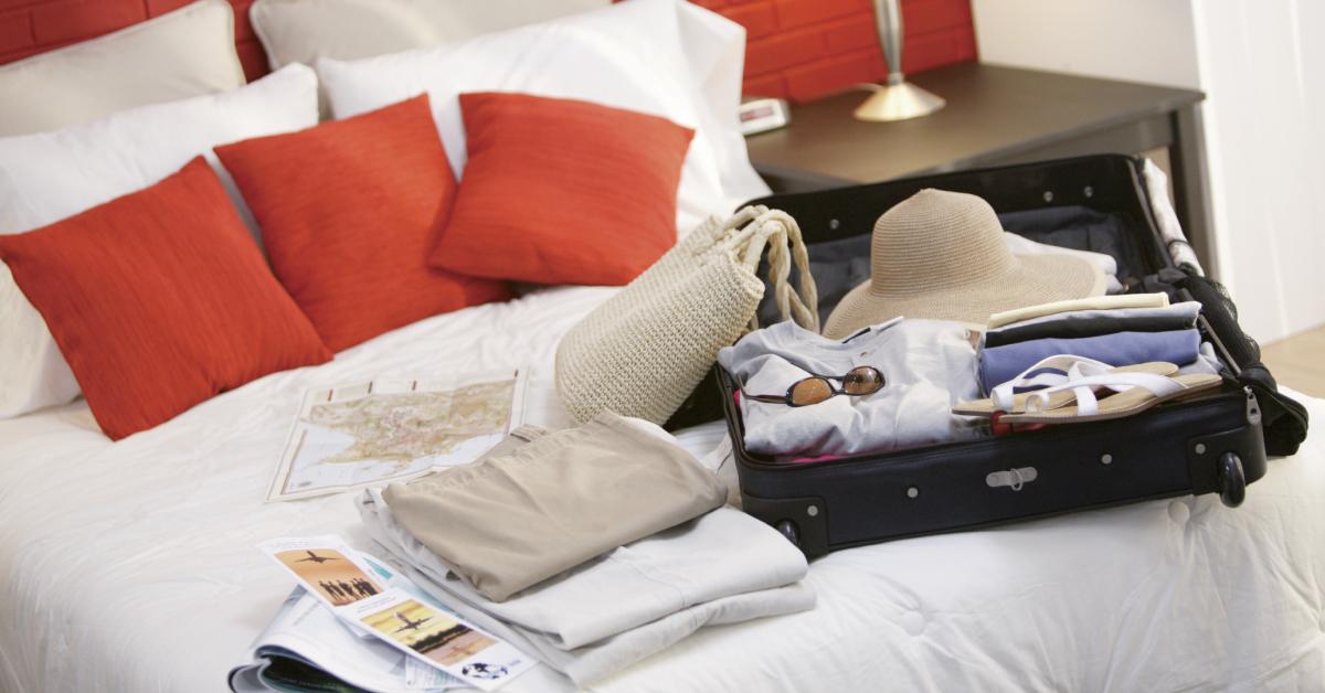 A suitcase and travel brochures on bed.