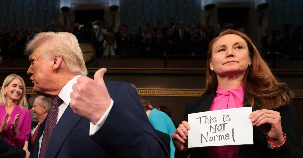 Donald Trump stands on the House floor as Rep. Melanie Stanley holds up a sign reading "This is Not Normal"