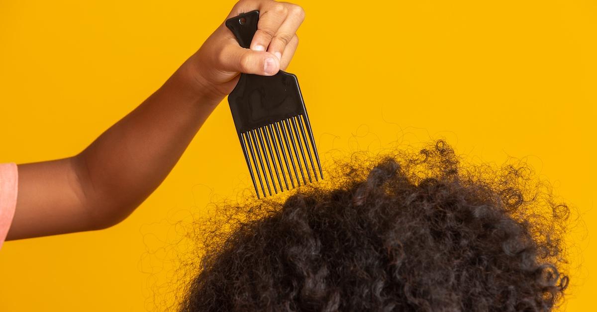 A person using a pick on curly hair