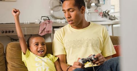 A Black man and his son playing video games