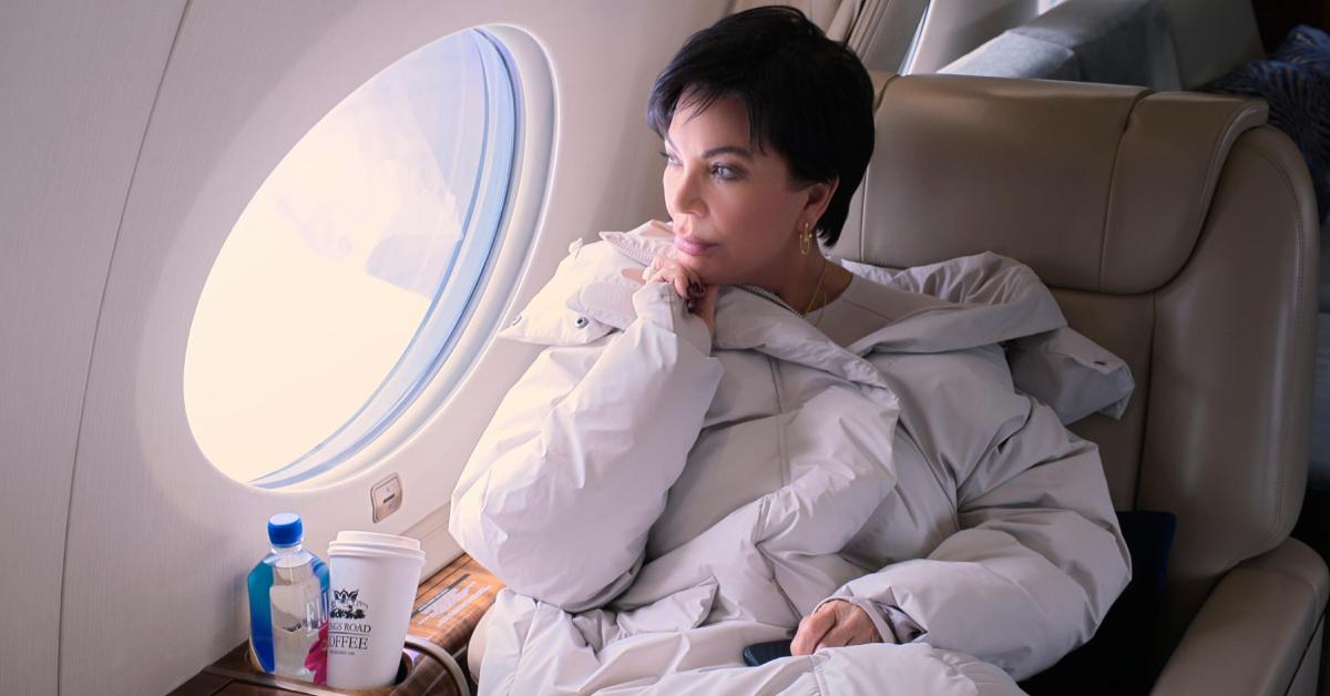 Kris, wearing an oversized white puffer jacket, sits in Kim's private jet and looks out the window in 'The Kardashians.'