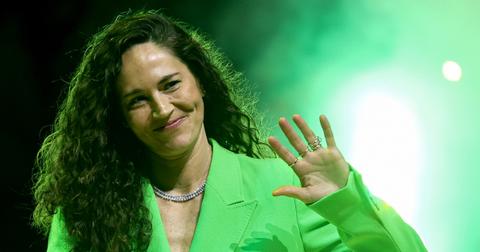 Sue Bird, sporting a bright green suit, waves to someone in the crowd during her jersey retirement ceremony on June 11, 2023.