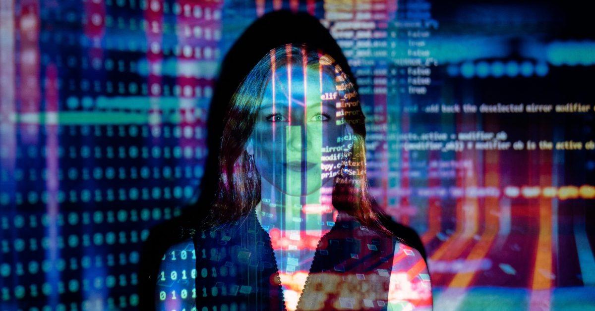 A woman sitting in front of a computer screen with code.