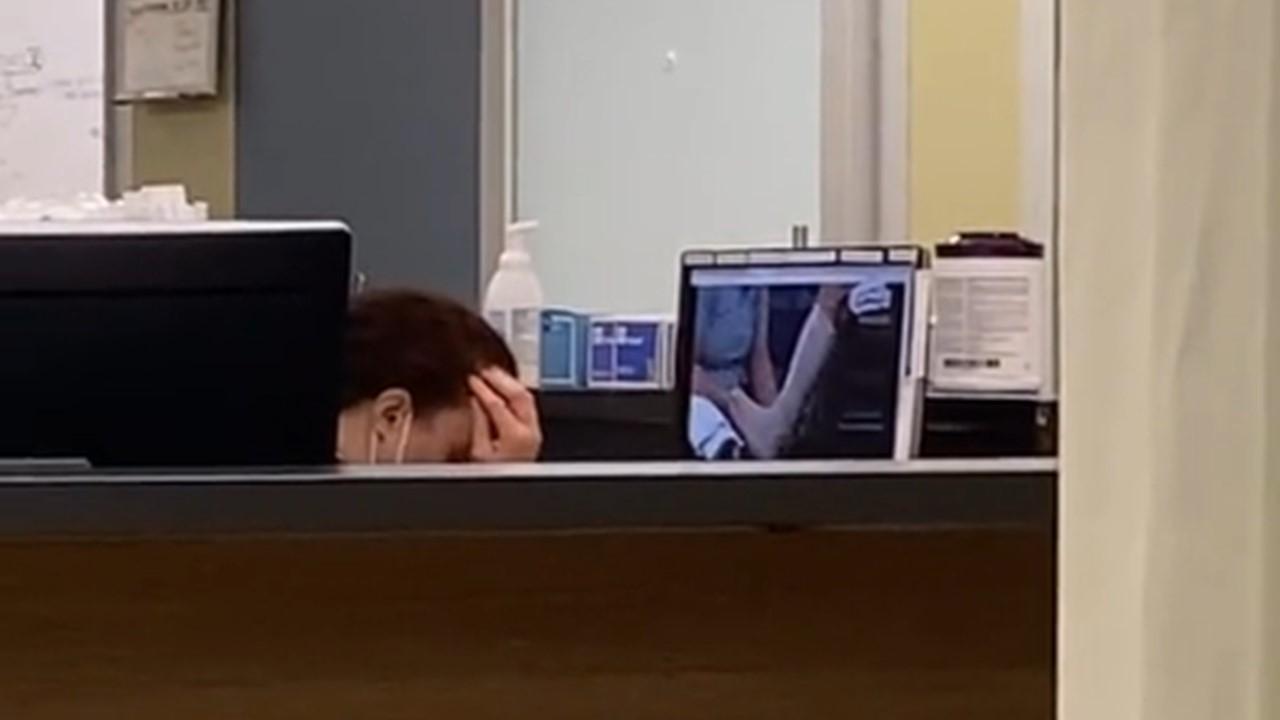 The doctor looks stressed as she watches the ankle-wrapping video on a computer