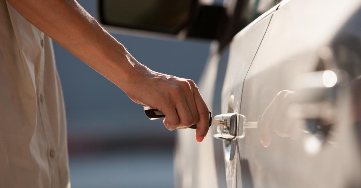 Woman unlocking car with a key - Stock Photo