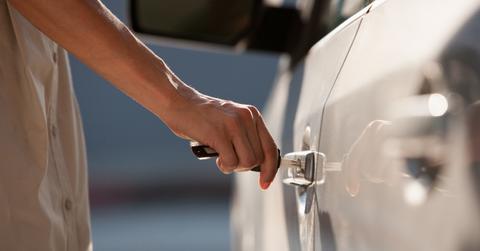 Woman unlocking car with a key - Stock Photo