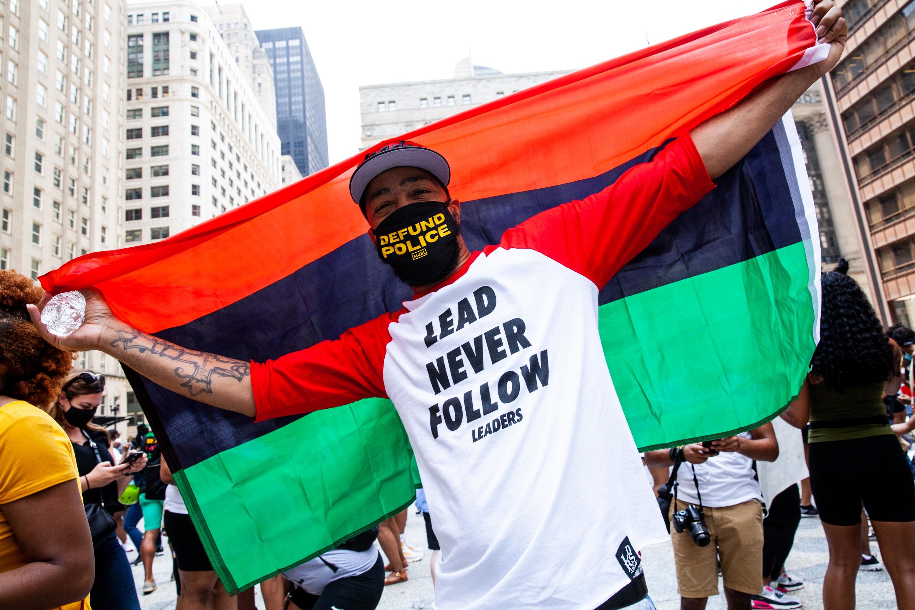 A male protester holding a Pan-African flag outside on Juneteenth.