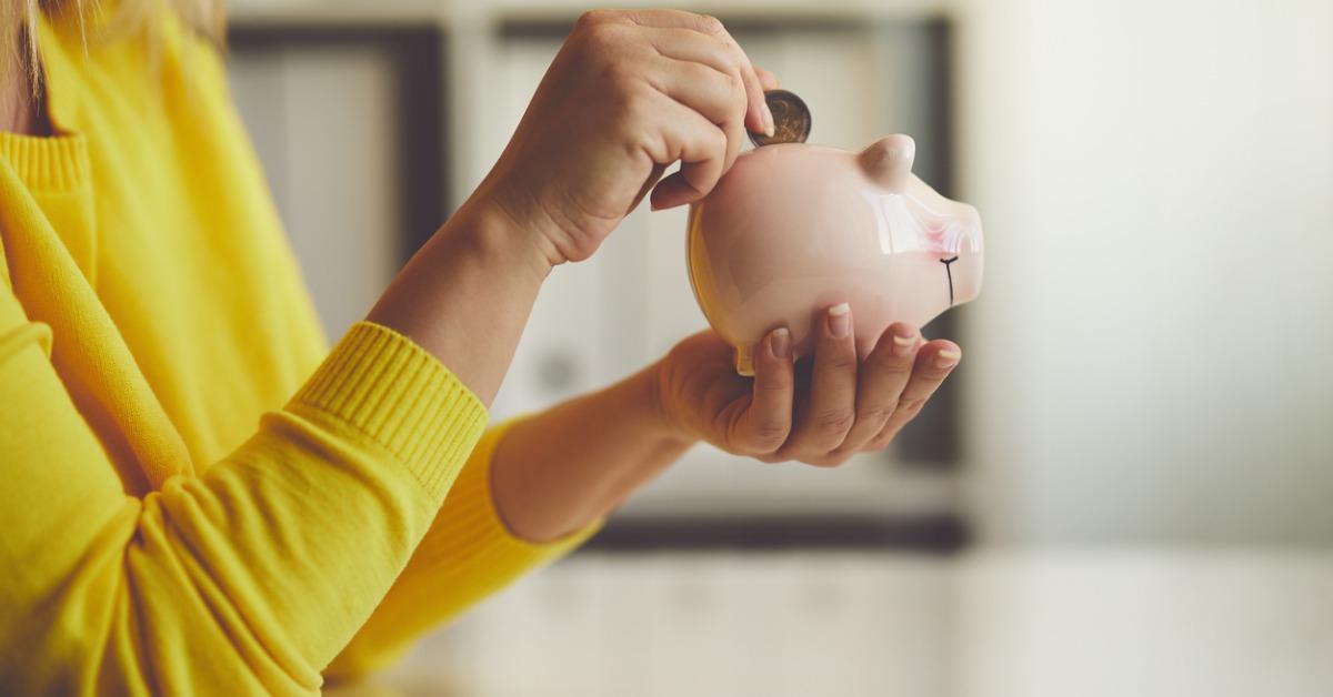 woman inserts a coin into a piggy bank picture id