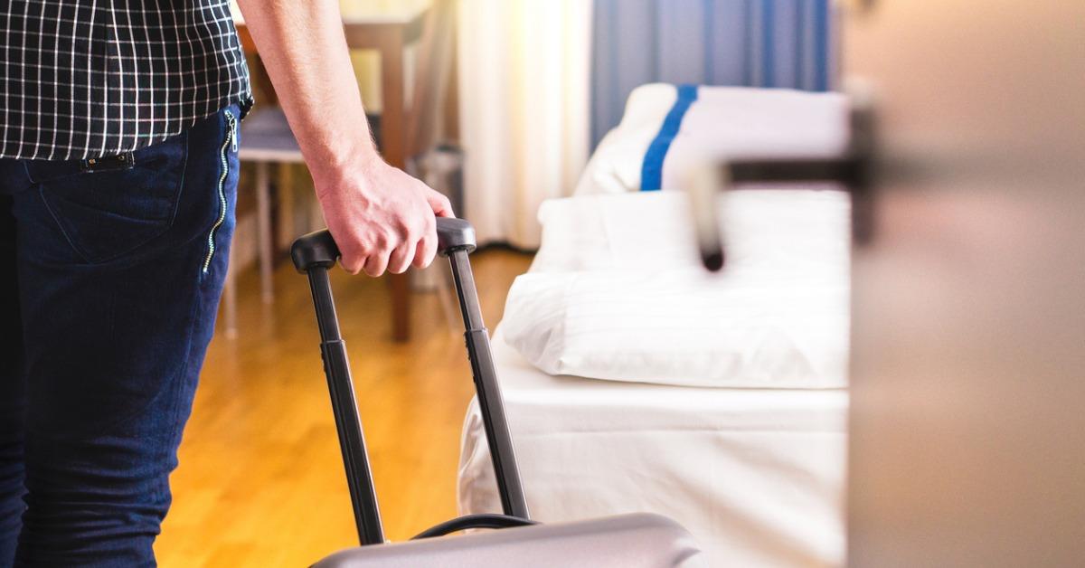 man pulling suitcase and entering hotel room traveler going in to or picture id