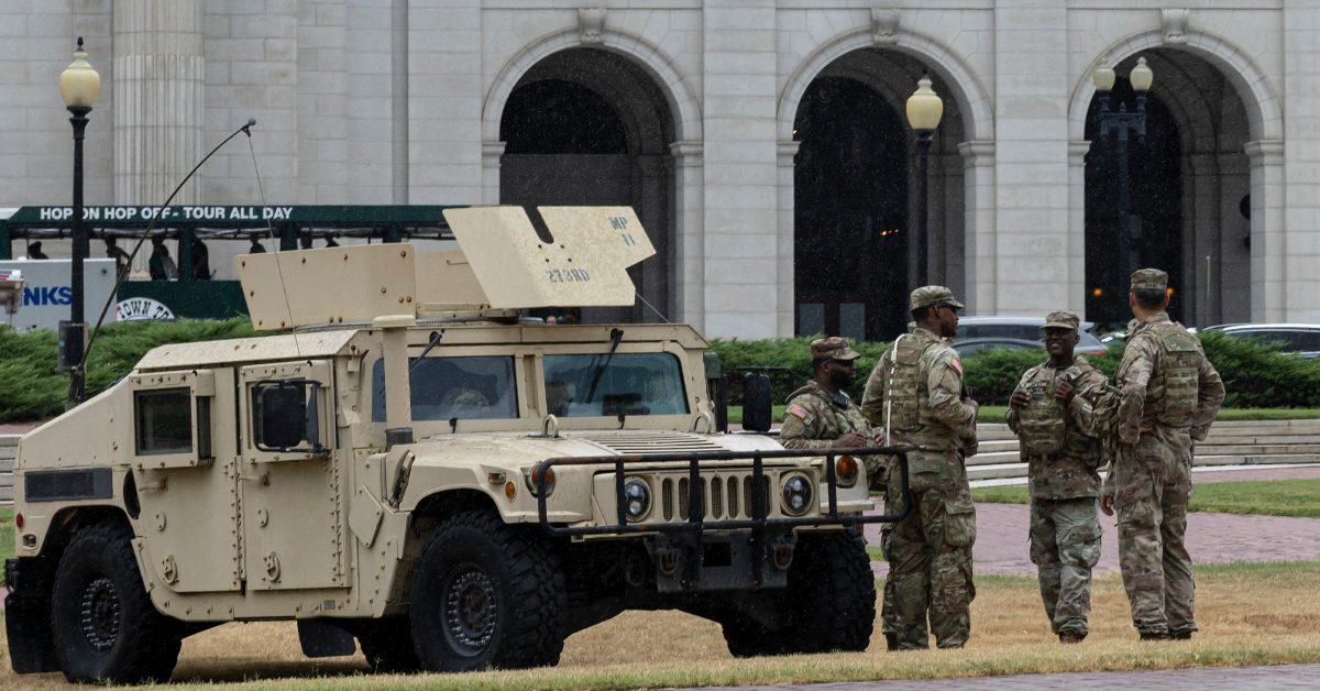 Military troops standing by a military truck.