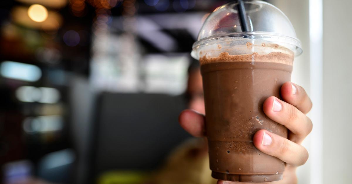 delicious chocolate frappe in plastic cup in manwomans hand with blur picture id