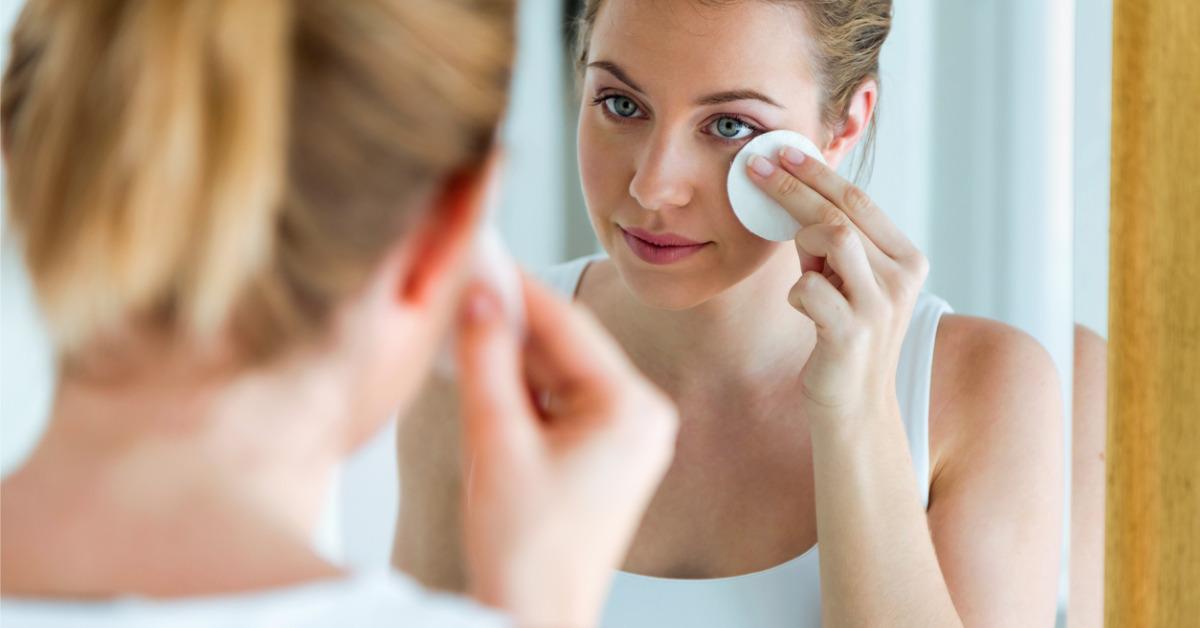 beautiful young woman is cleaning her face while looking in the in picture id