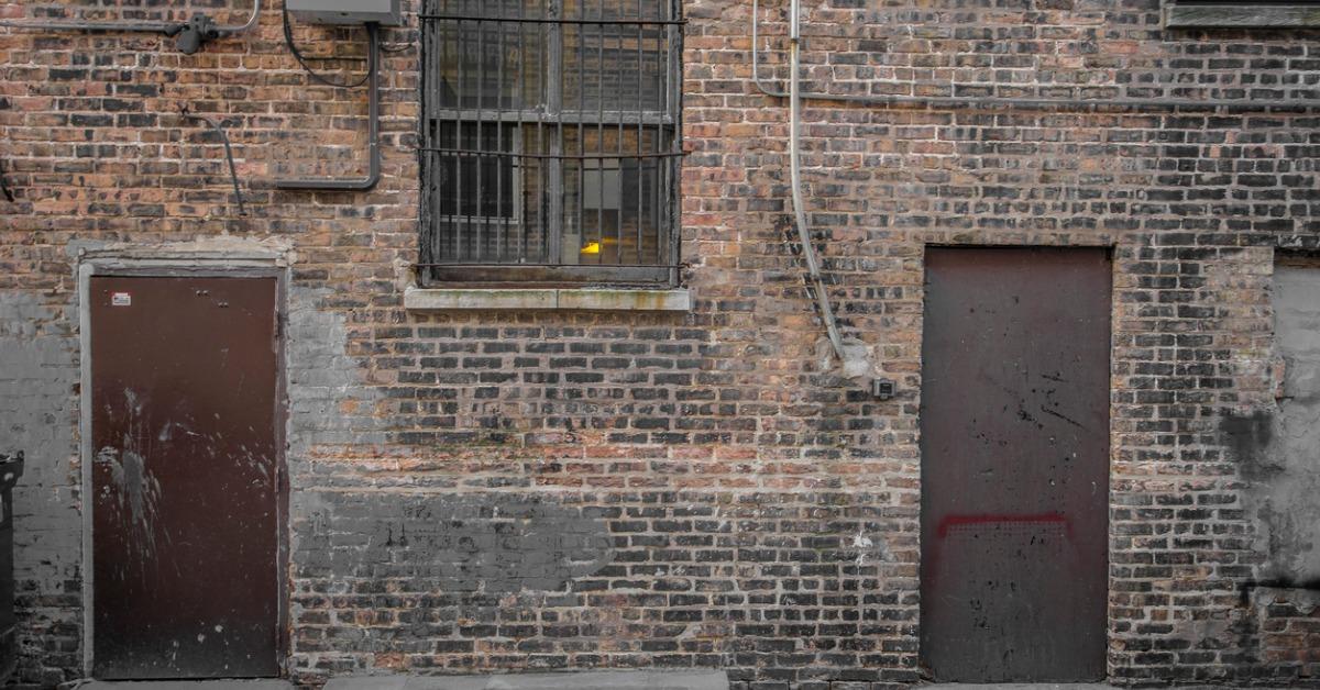 brick wall with brown doors and barred window picture id